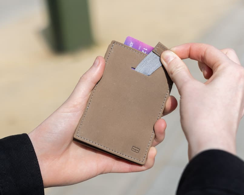 Outside image of the front view of Cavare Magic Wallet Vintage in Metal Grey with a hand pulling the tab with a card coming out.