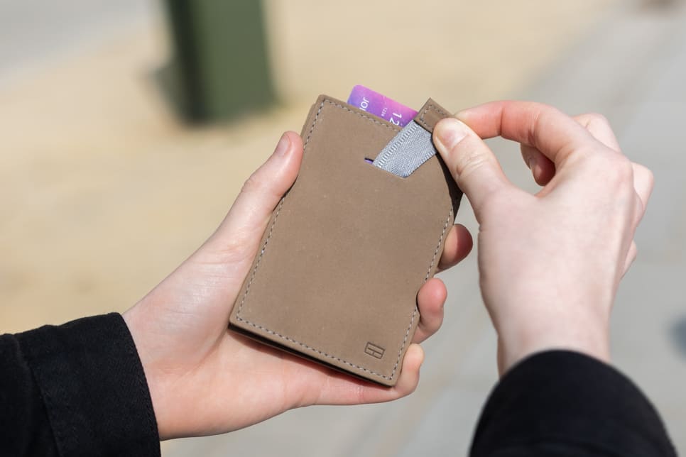 Outside image of the front view of Cavare Magic Wallet Vintage in Metal Grey with a hand pulling the tab with a card coming out.