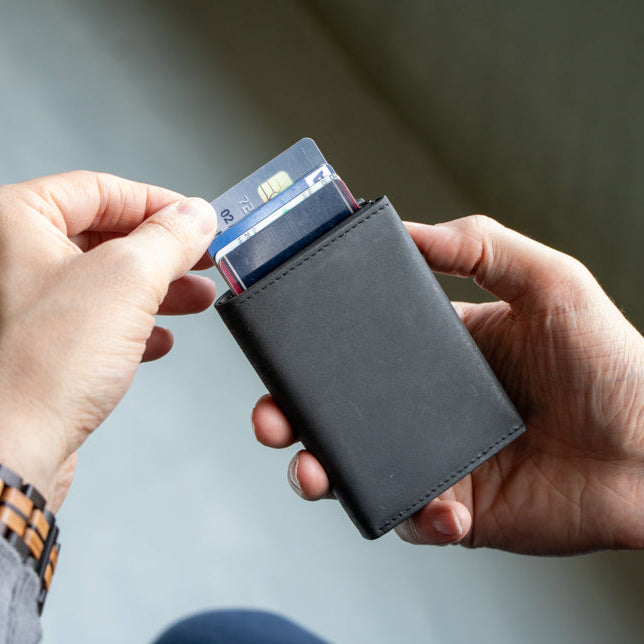 Person holding a black wallet with a card