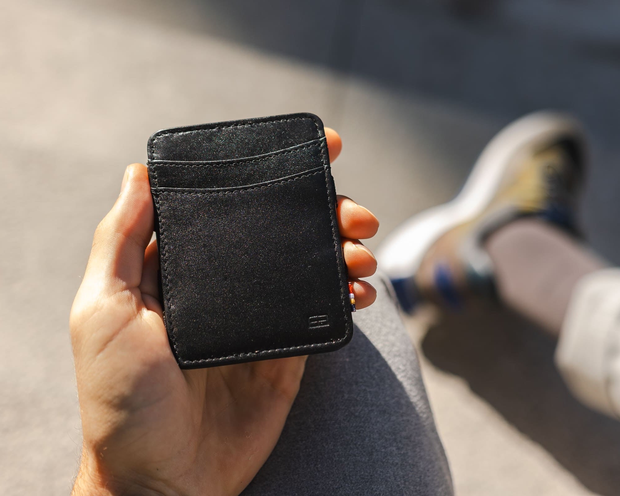 Hand holding the Garzini Urban Magic Wallet in black leather, demonstrating its compact size and sleek design.