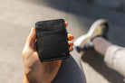 Hand holding the Garzini Urban Magic Wallet in black leather, demonstrating its compact size and sleek design.