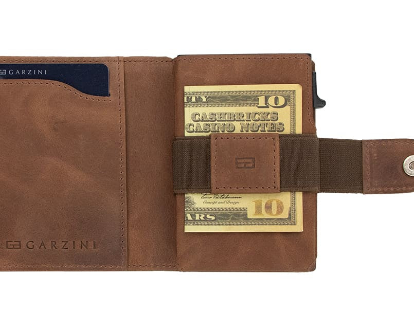 Open Garzini Metal Wallet in brushed brown leather, holding a stack of cash
