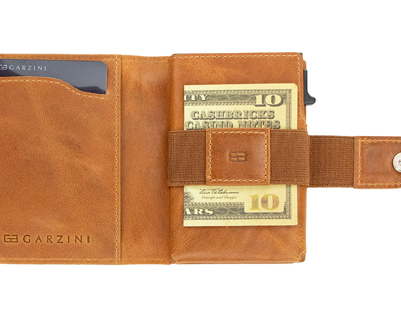 Open Garzini Metal Wallet in brushed cognac leather, holding a stack of cash