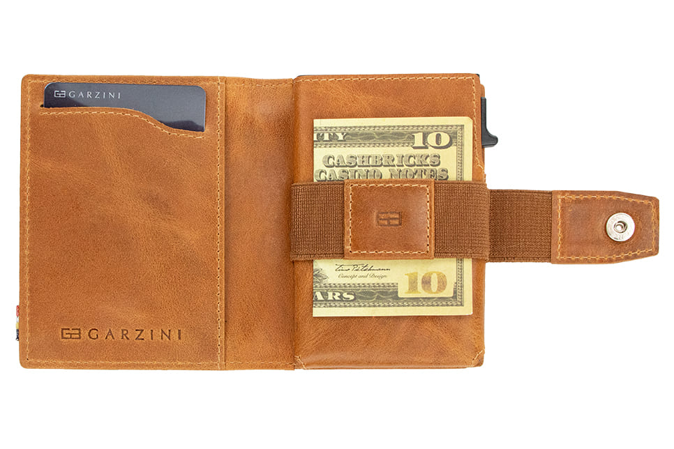 Open Garzini Metal Wallet in brushed cognac leather, holding a stack of cash