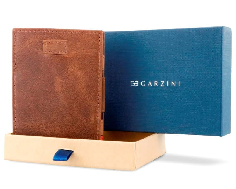 Half-open blue box with Garzini brand name Inside the box, the Brushed Brown wallet is wrapped in tissue paper, placed in a light cardboard box with a blue strap.