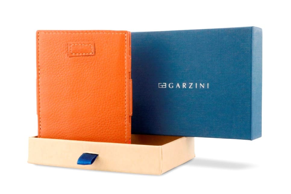 Half-open blue box with Garzini brand name Inside the box, the Cognac Brown wallet is wrapped in tissue paper, placed in a light cardboard box with a blue strap.