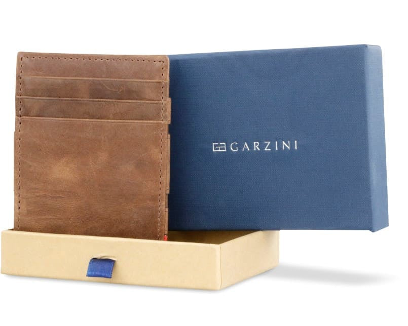 Half-open blue box with Garzini brand name Inside the box, the Brushed Brown wallet is wrapped in tissue paper, placed in a light cardboard box with a blue strap.