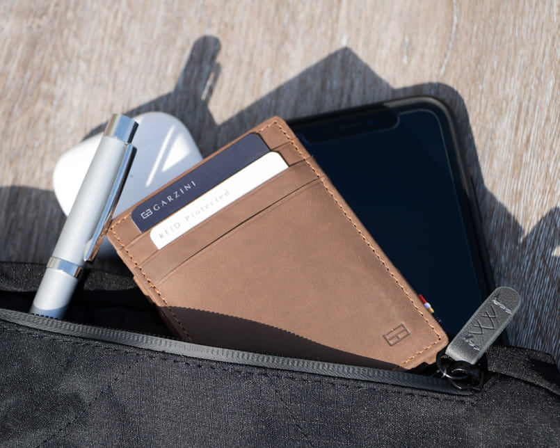 A hand holding the Essenziale Magic Wallet Vintage in Metal Grey with 2 cards in the card slot.