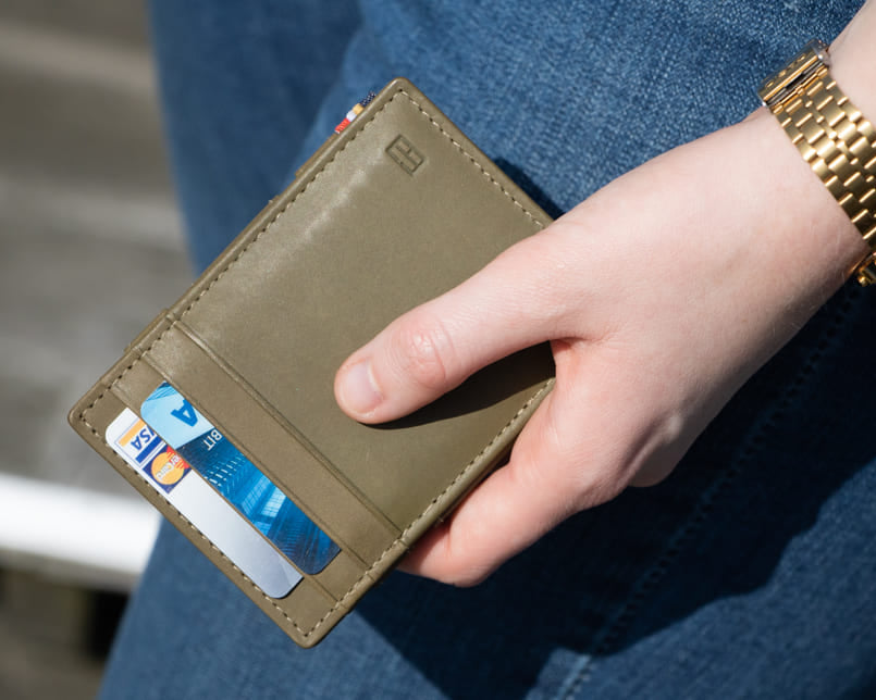 A hand holding the Essenziale Magic Wallet Vintage in Olive Green with 2 cards in the card slot. 