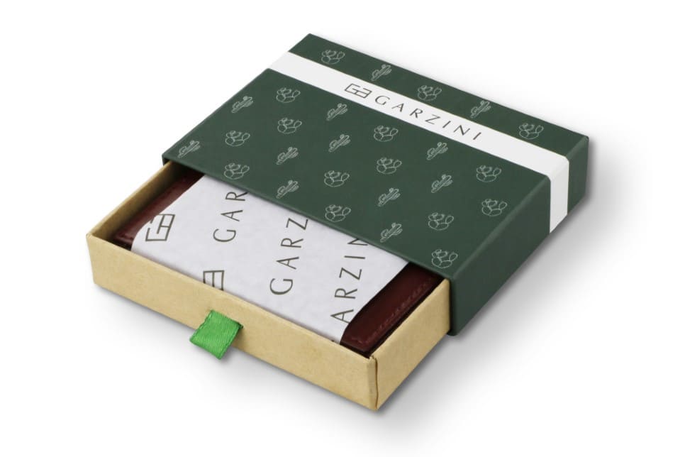 Half-open green box with Garzini brand name, featuring cactus icons. Inside the box, the cactus Burgundy wallet is wrapped in tissue paper, placed in a light cardboard box with a green strap.