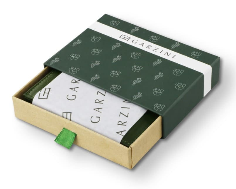 Half-open green box with Garzini brand name, featuring cactus icons. Inside the box, the cactus Green wallet is wrapped in tissue paper, placed in a light cardboard box with a green strap.