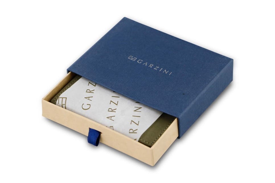 Half-open blue box with Garzini brand name. Inside the box, the Olive Green wallet is wrapped in tissue paper, placed in a light cardboard box with a blue strap
