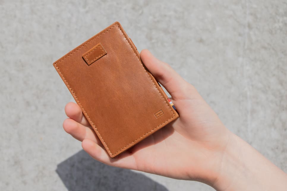 "Outside image of the front view of Cavare Magic Wallet Brushed in Brushed Cognac with a hand holding it open. "
