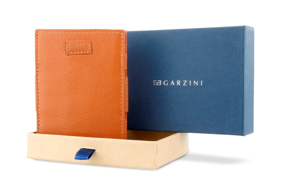 Half-open blue box with Garzini brand name Inside the box, the Garzini wallet is wrapped in tissue paper, placed in a light cardboard box with a blue strap.
