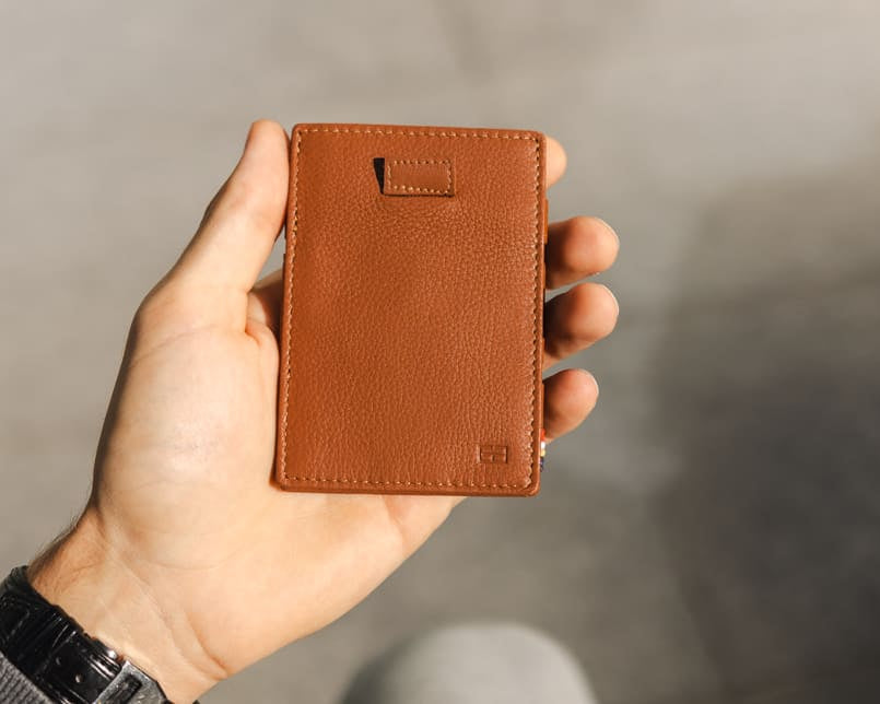 A hand holding the Garzini Cavare Cognac nappa wallet