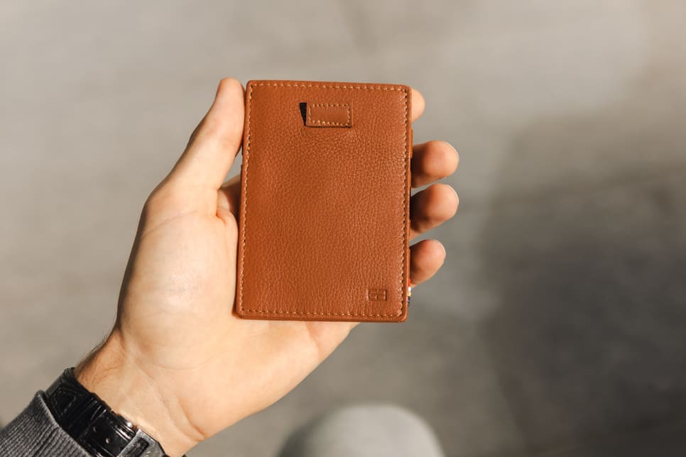 A hand holding the Garzini Cavare Cognac nappa wallet