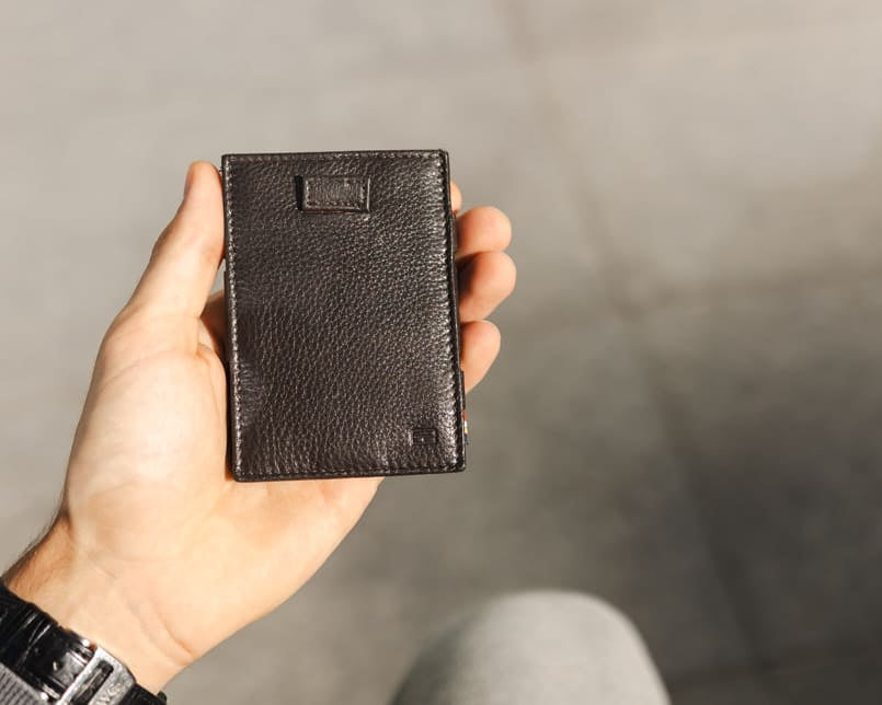 A hand holding the Garzini Cavare Raven Black nappa wallet