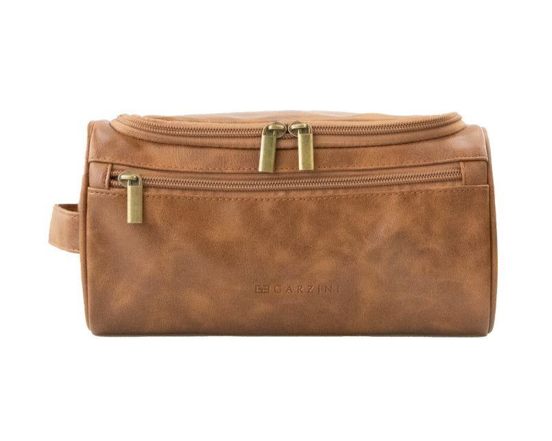 Close-up of Cognac Garzini Toiletry Bag front side, featuring premium vegan leather and brass zipper details.