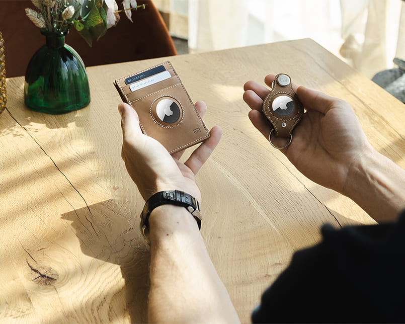 2 hands holding an airtag wallet and an airtag key holder