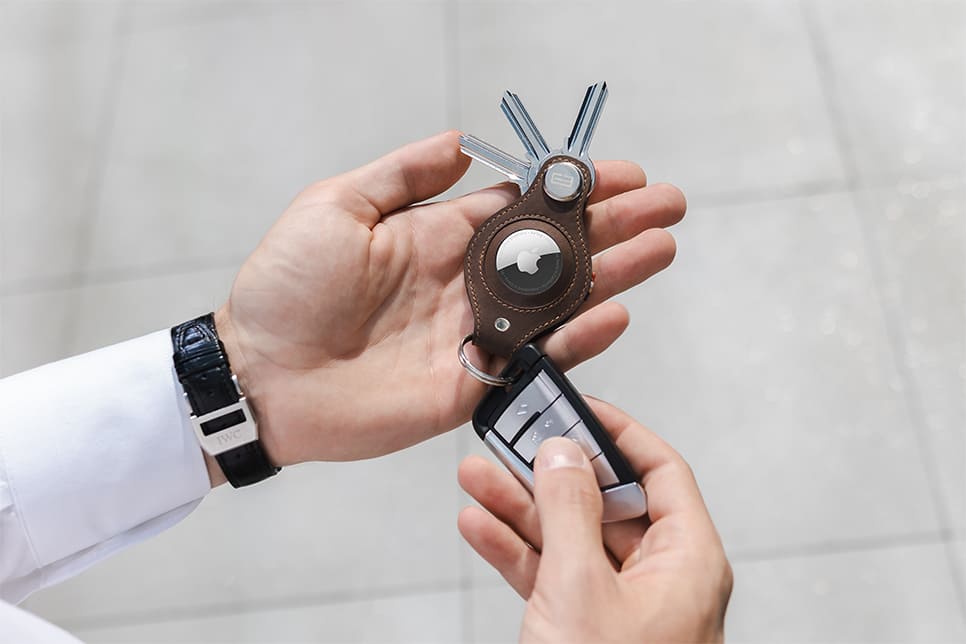 A hand holding the airtag key holder