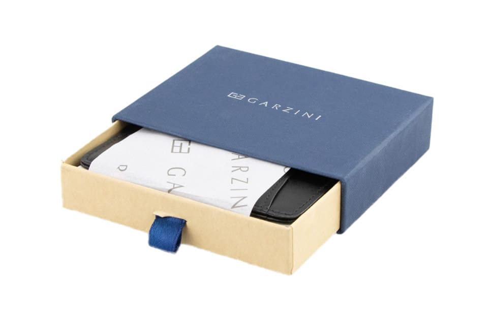 Half-open blue box with Garzini brand name Inside the box, the Black Classic Magic Coin Wallet is wrapped in tissue paper, placed in a light cardboard box with a blue strap.