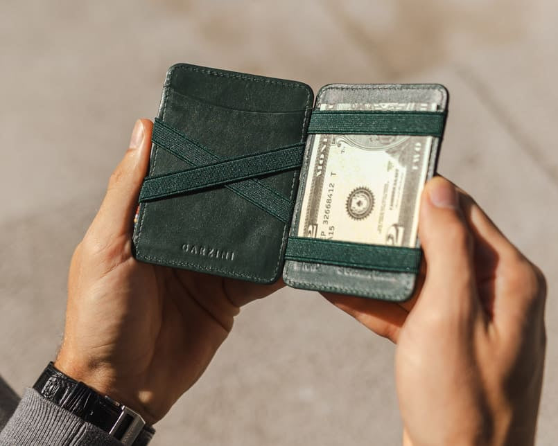 A hand holding the wallet with money inside.