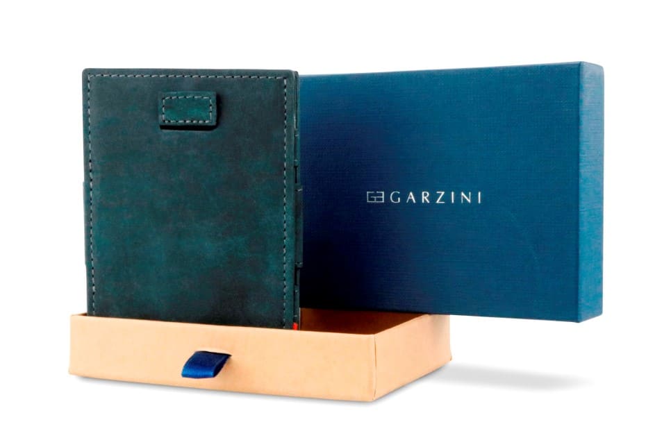 Half-open blue box with Garzini brand name Inside the box, the Carbon Black wallet is wrapped in tissue paper, placed in a light cardboard box with a blue strap.