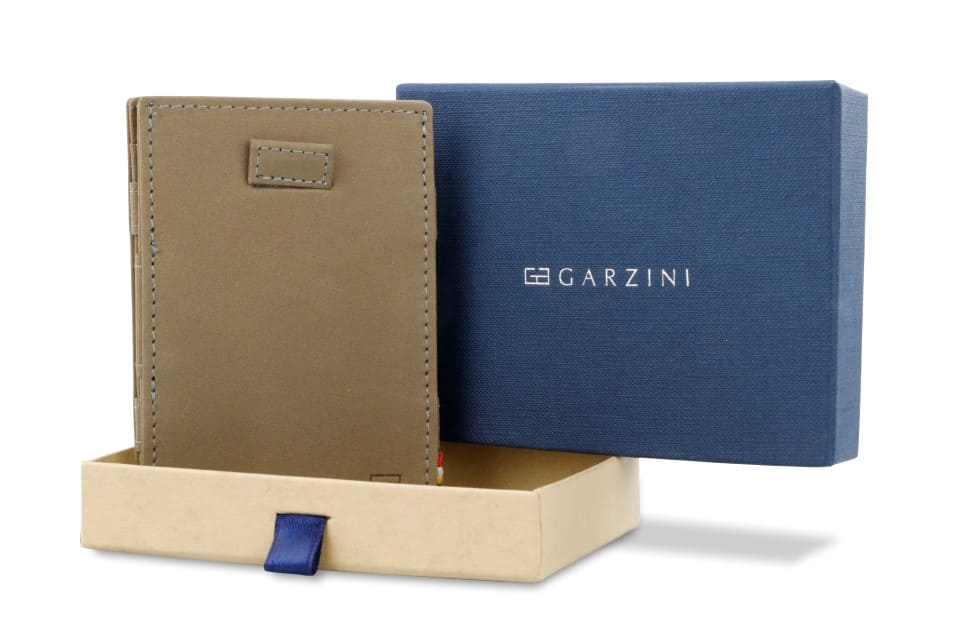 Half-open blue box with Garzini brand name Inside the box, the Metal Grey wallet is wrapped in tissue paper, placed in a light cardboard box with a blue strap.