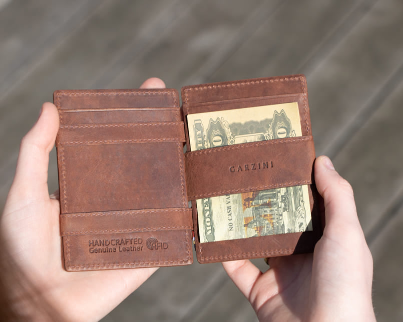 A hand holding the Essenziale Magic Wallet Brushed in Brushed Brown with 2 cards in the card slot.
