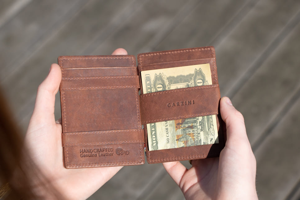 A hand holding the Essenziale Magic Wallet Brushed in Brushed Brown with 2 cards in the card slot.