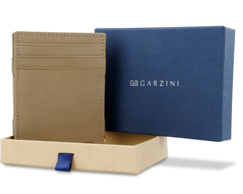 Half-open blue box with Garzini brand name Inside the box, the Metal Grey wallet is wrapped in tissue paper, placed in a light cardboard box with a blue strap.