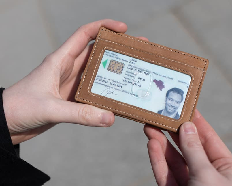 Two hands holding the Essenziale Magic Wallet ID Window Vintage in Camel Brown with an ID window.