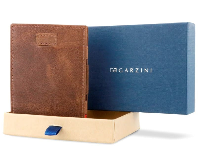 Half-open blue box with Garzini brand name Inside the box, the Brushed Brown wallet is wrapped in tissue paper, placed in a light cardboard box with a blue strap.