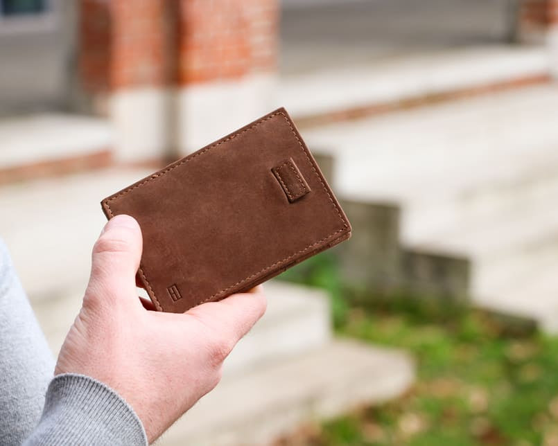 Outside image of the front view of Cavare Magic Wallet Brushed in Brushed Brown with a hand holding it open.