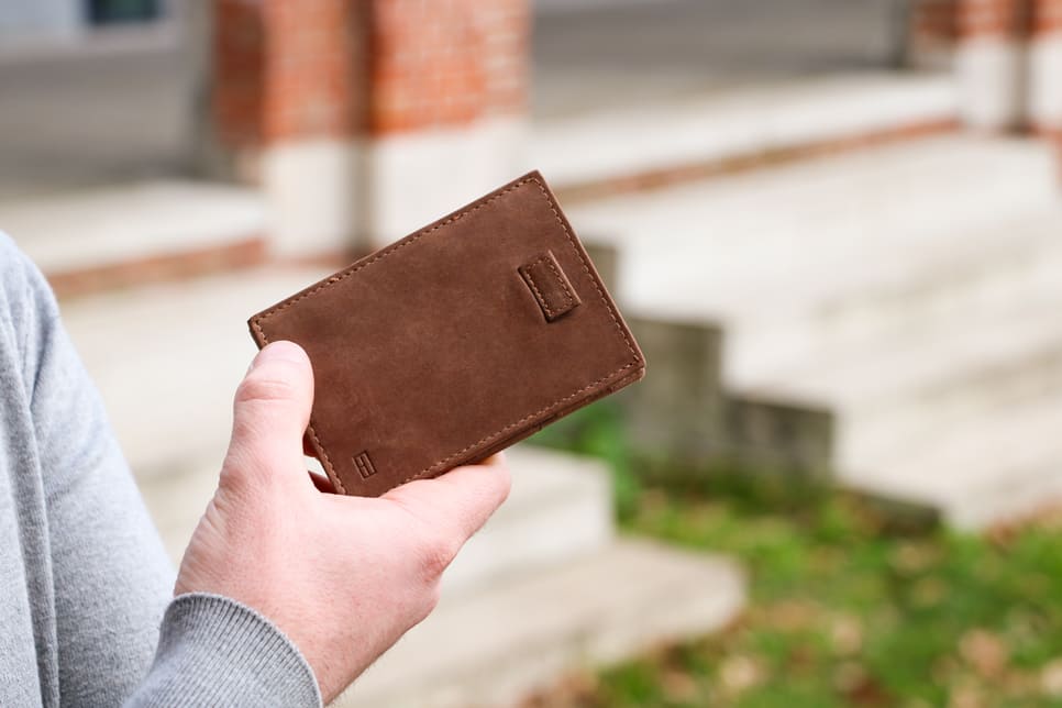 Outside image of the front view of Cavare Magic Wallet Brushed in Brushed Brown with a hand holding it open.