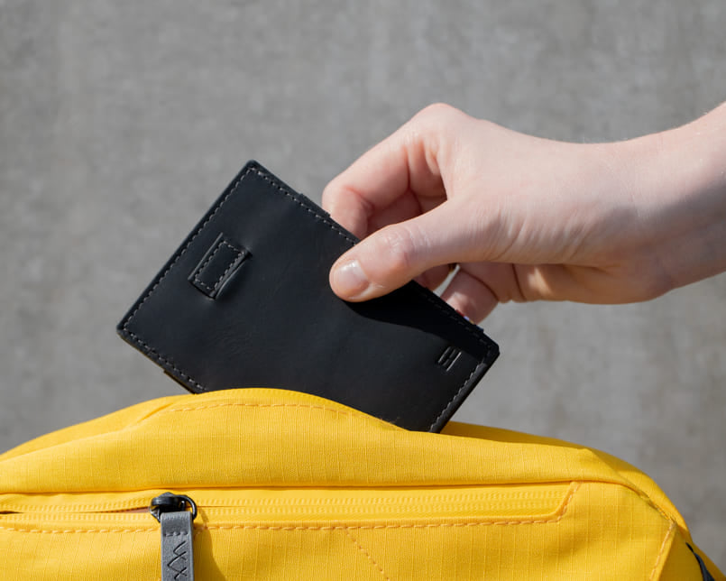 A Cavare Magic Wallet Card Sleeve Vintage Carbon Black hold by a hand put into a bag.