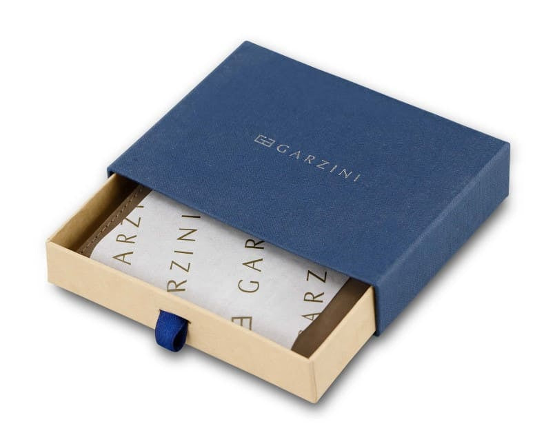 Half-open blue box with Garzini brand name Inside the box, the Java Brown wallet is wrapped in tissue paper, placed in a light cardboard box with a blue strap.