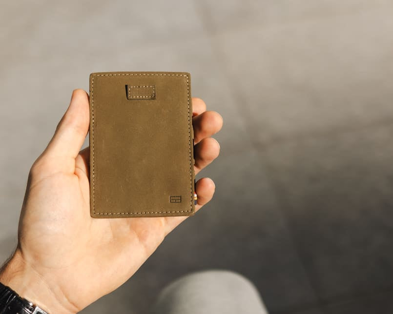A hand holding the Garzini Cavare Olive green wallet