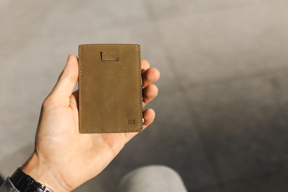 A hand holding the Garzini Cavare Olive green wallet