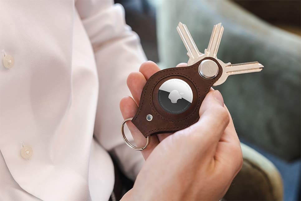 A hand holding the airtag key holder