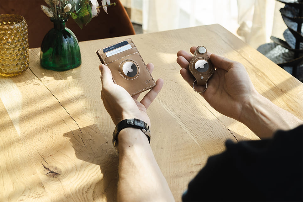 2 hands holding an airtag wallet and an airtag key holder
