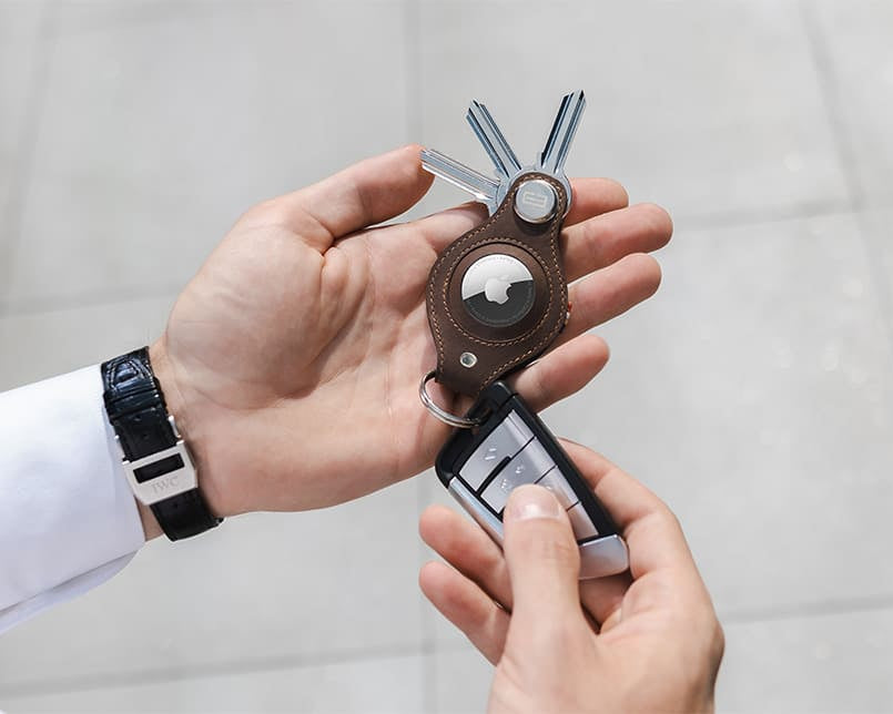 A hand holding the airtag key holder